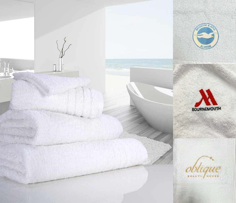 Bale of white towels in a bathroom with examples of embroidered logos