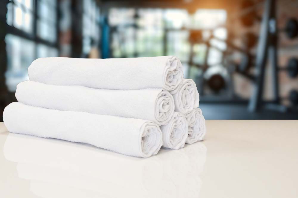 Rolled white 360gsm gym towels in a gym setting