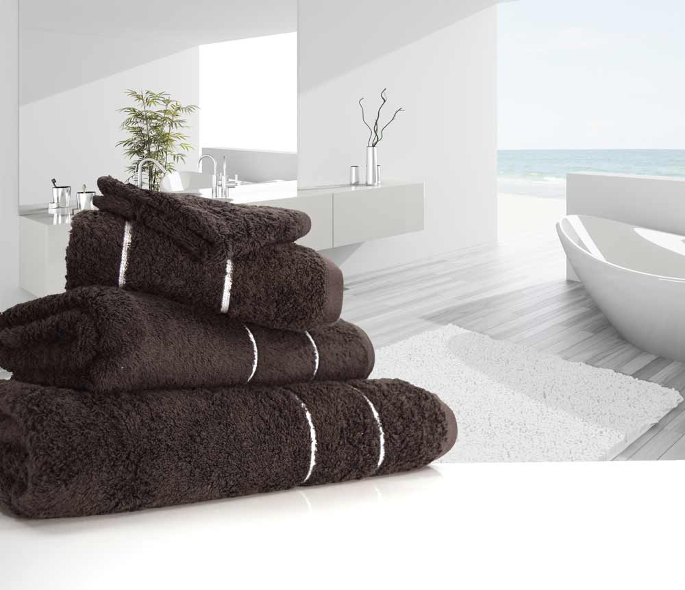 Neatly folded dark chocolate 750 gsm Eqyptian Quality cotton towels placed next to a bathtub