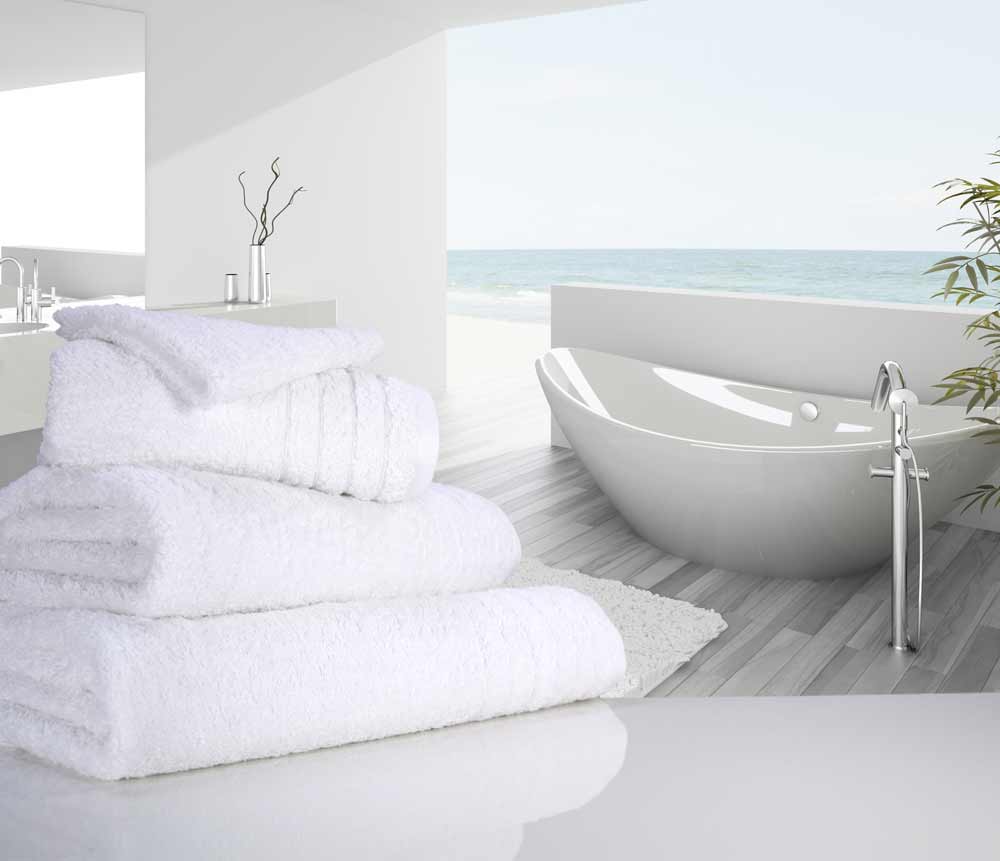Neatly folded snow white 650gsm luxury towels near a bathtub