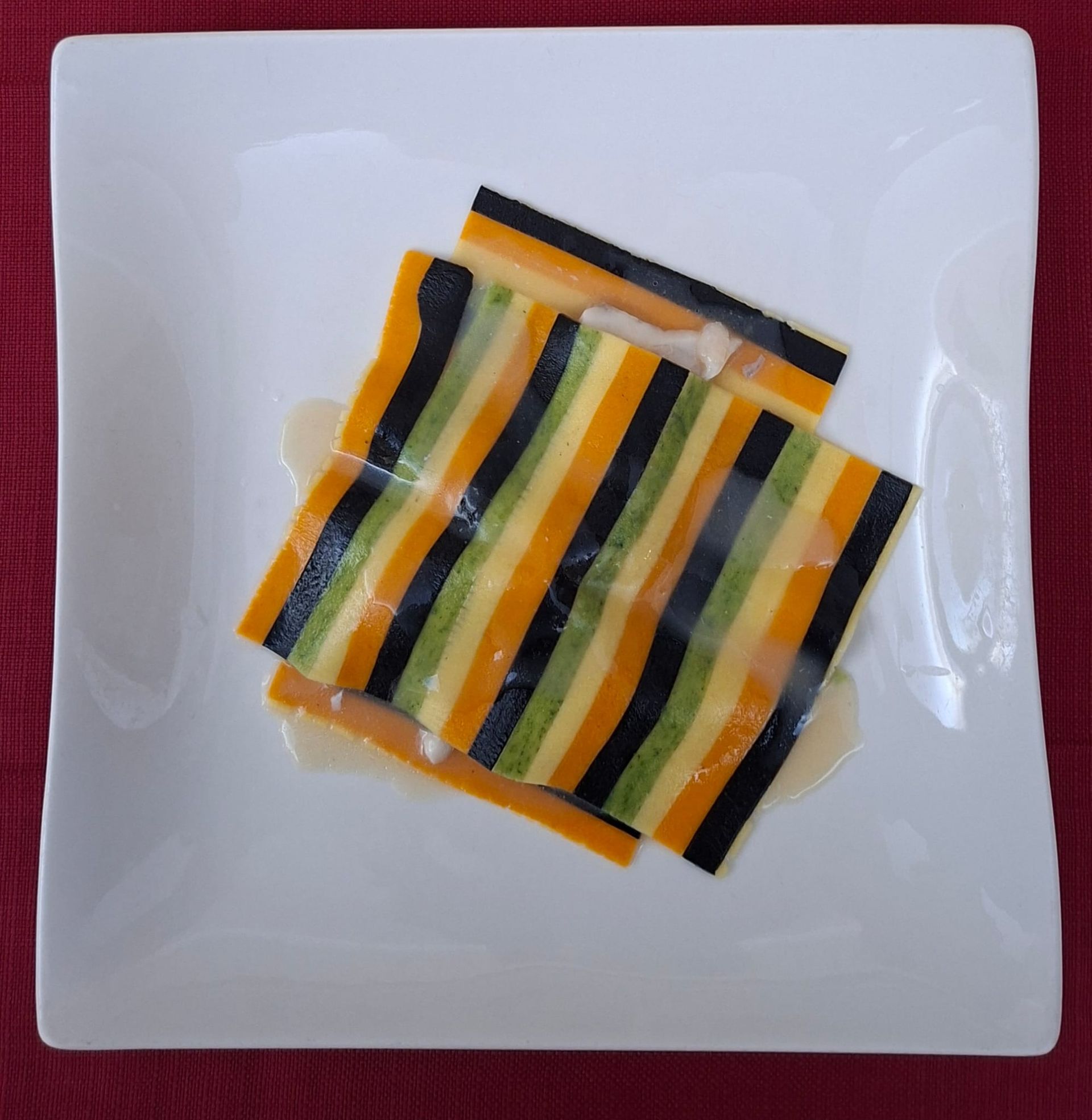 Piatto da dessert con tre delizie: palla di gelato, diamante di cioccolato e crostatina di frutta. Cosparso di zucchero a velo e scorza d'arancia.