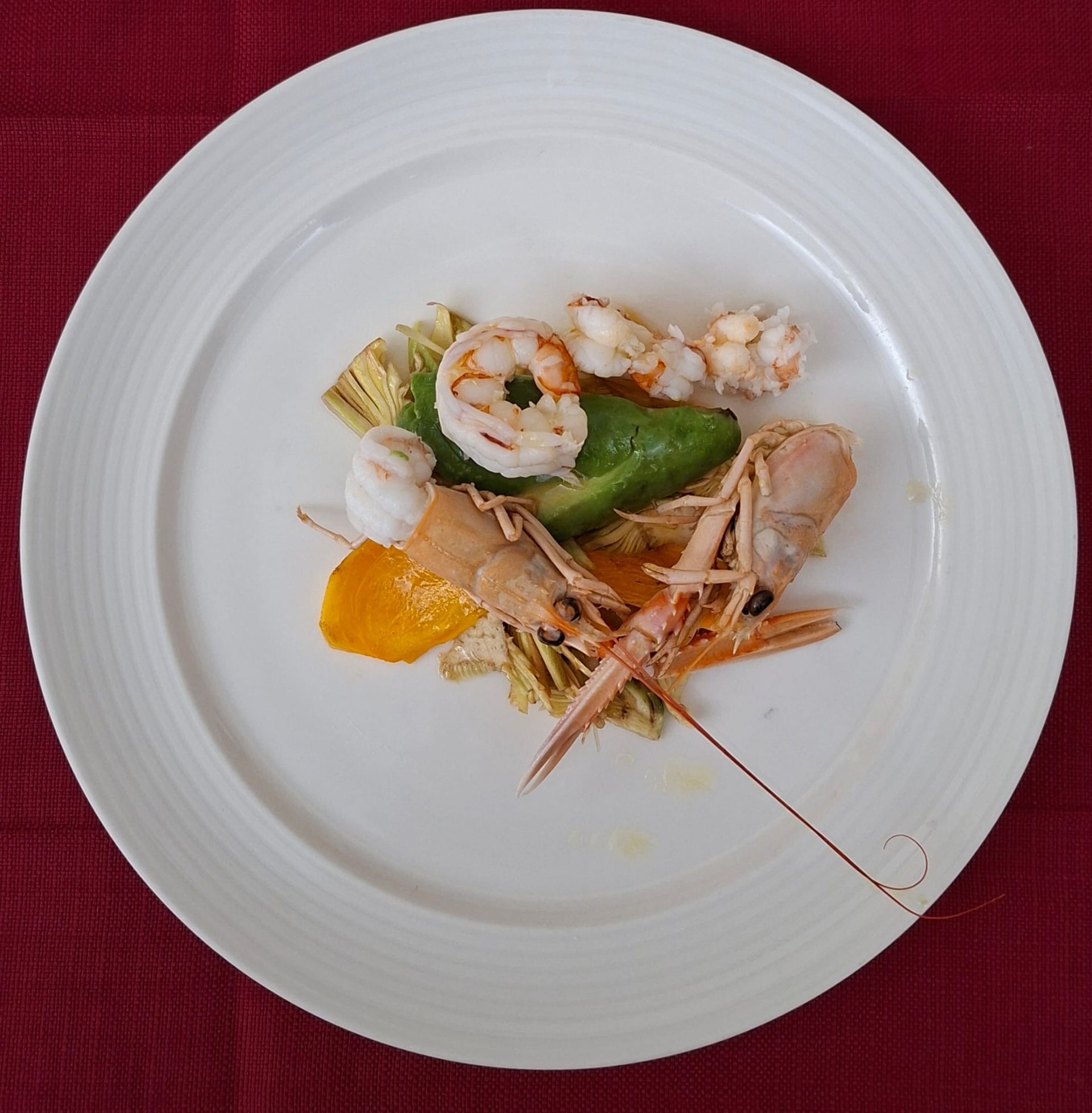 Risotto servito in un piatto quadrato bianco su una tovaglia gialla.