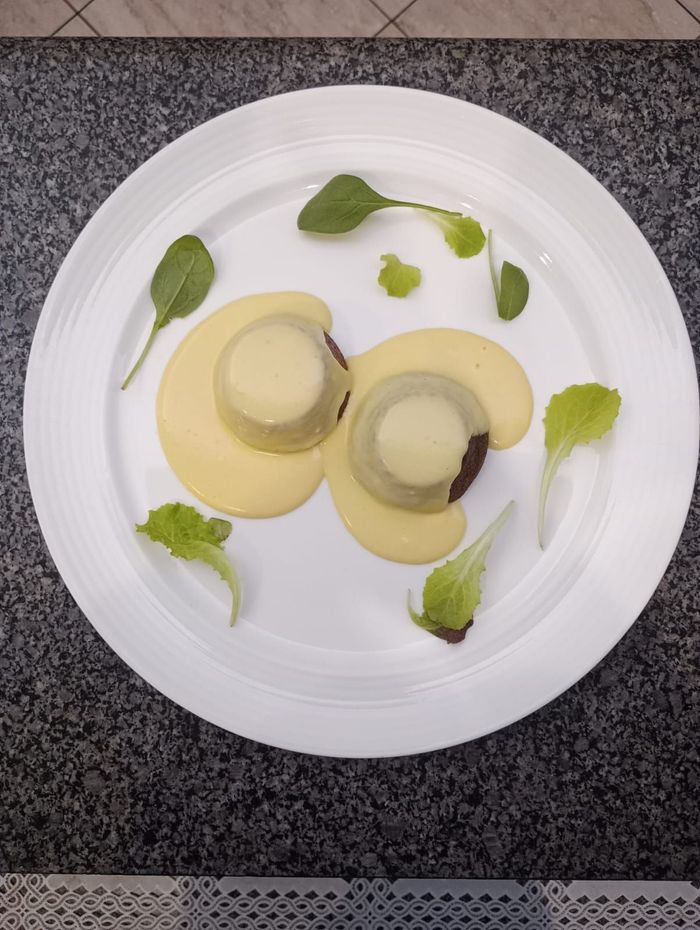 Piatto elegante con due cappelli di funghi, salsa gialla e guarnizione di foglie verdi.