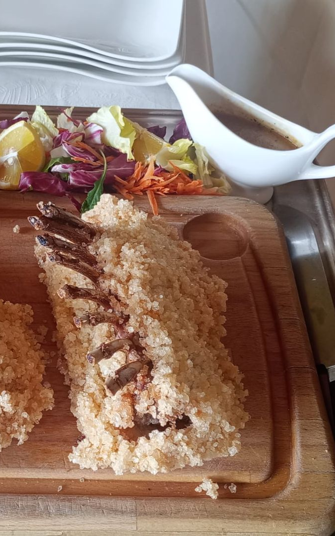 Risotto servito in un piatto quadrato bianco su una tovaglia gialla.