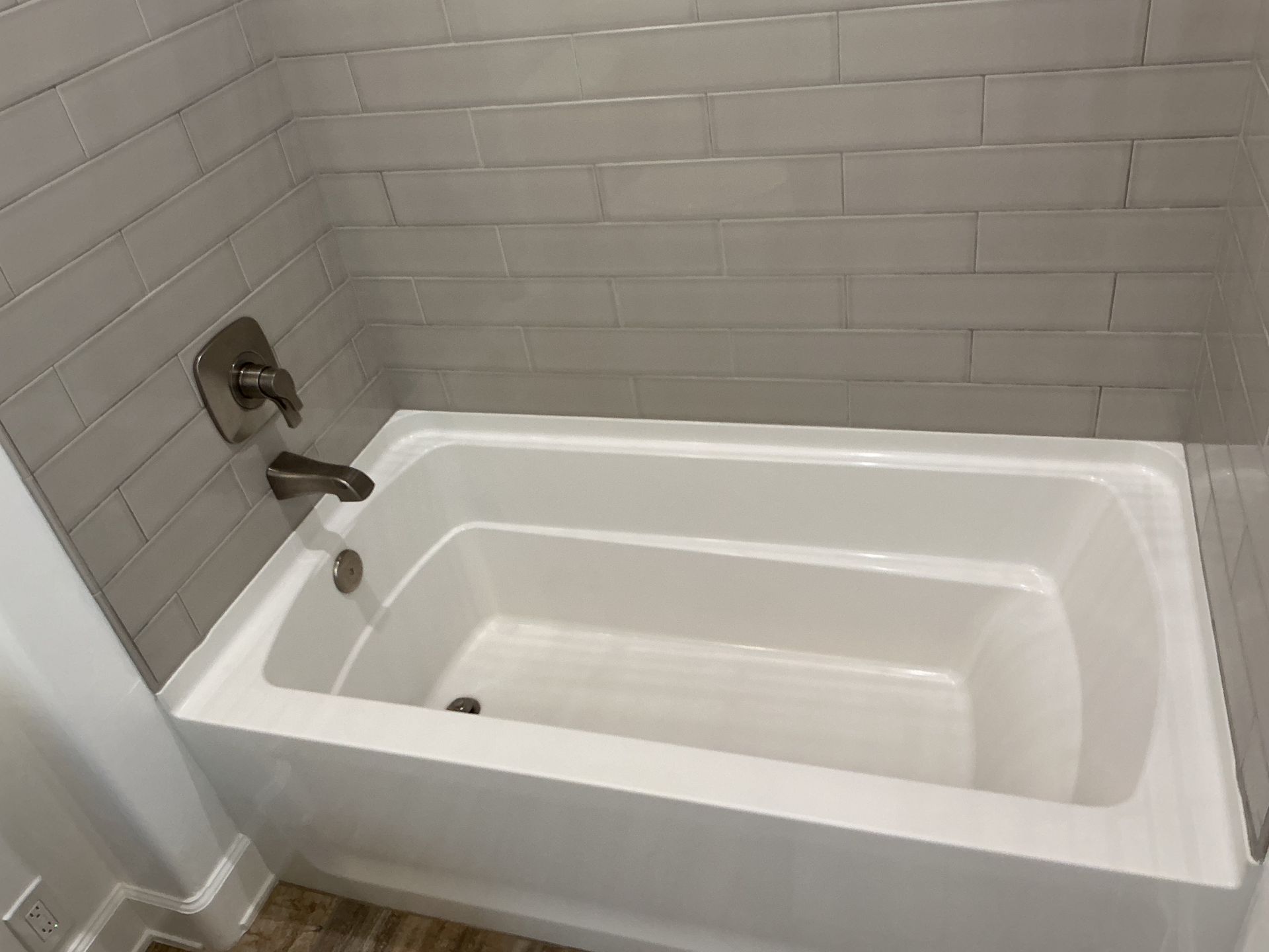 White bathtub with faucet and gray tiled wall.