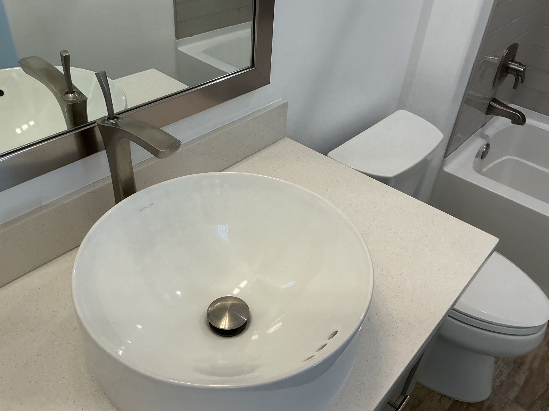 Bathroom with a white vessel sink, countertop, toilet, and bathtub.