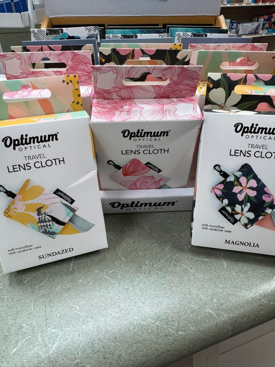 Three boxes of optimum lens cloths are sitting on a counter.