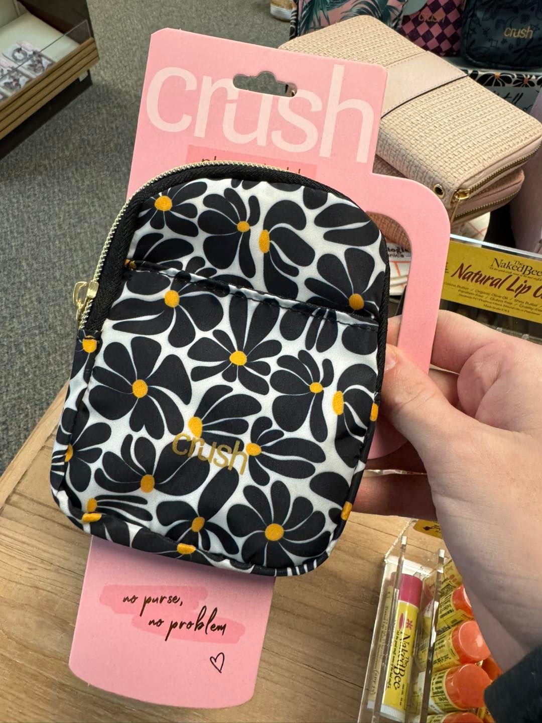 A person is holding a small black and white purse with yellow flowers on it.