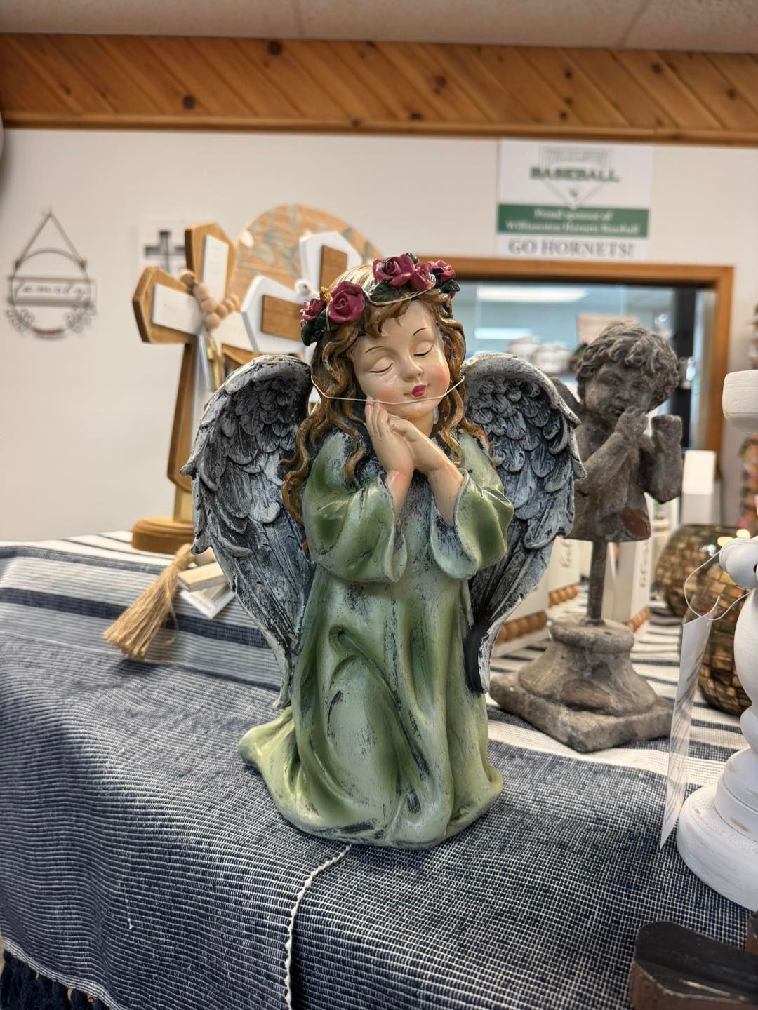 A statue of an angel with a flower crown on her head is sitting on a table.