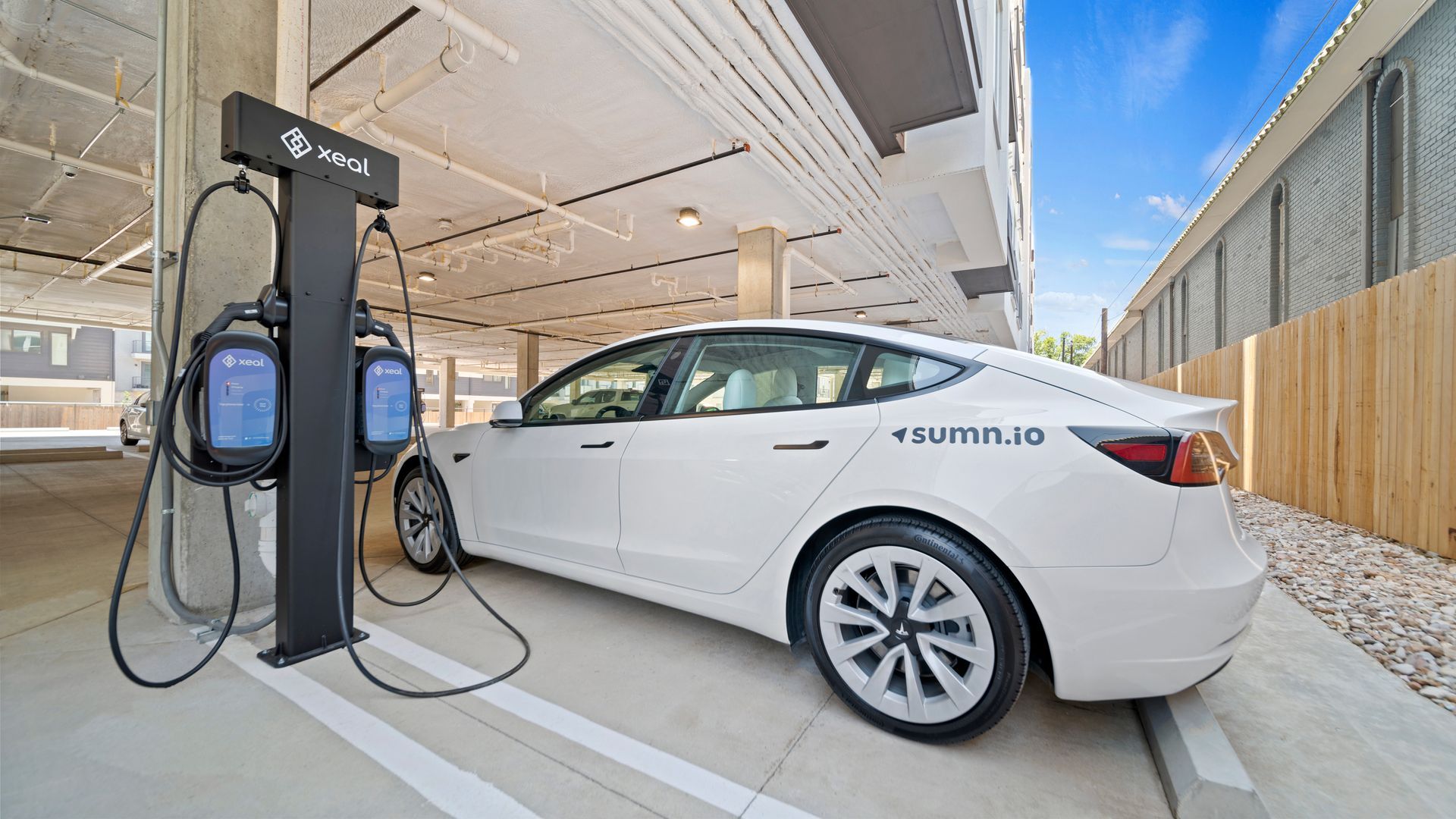 White Tesla plugged into a charging station under a covered parking area