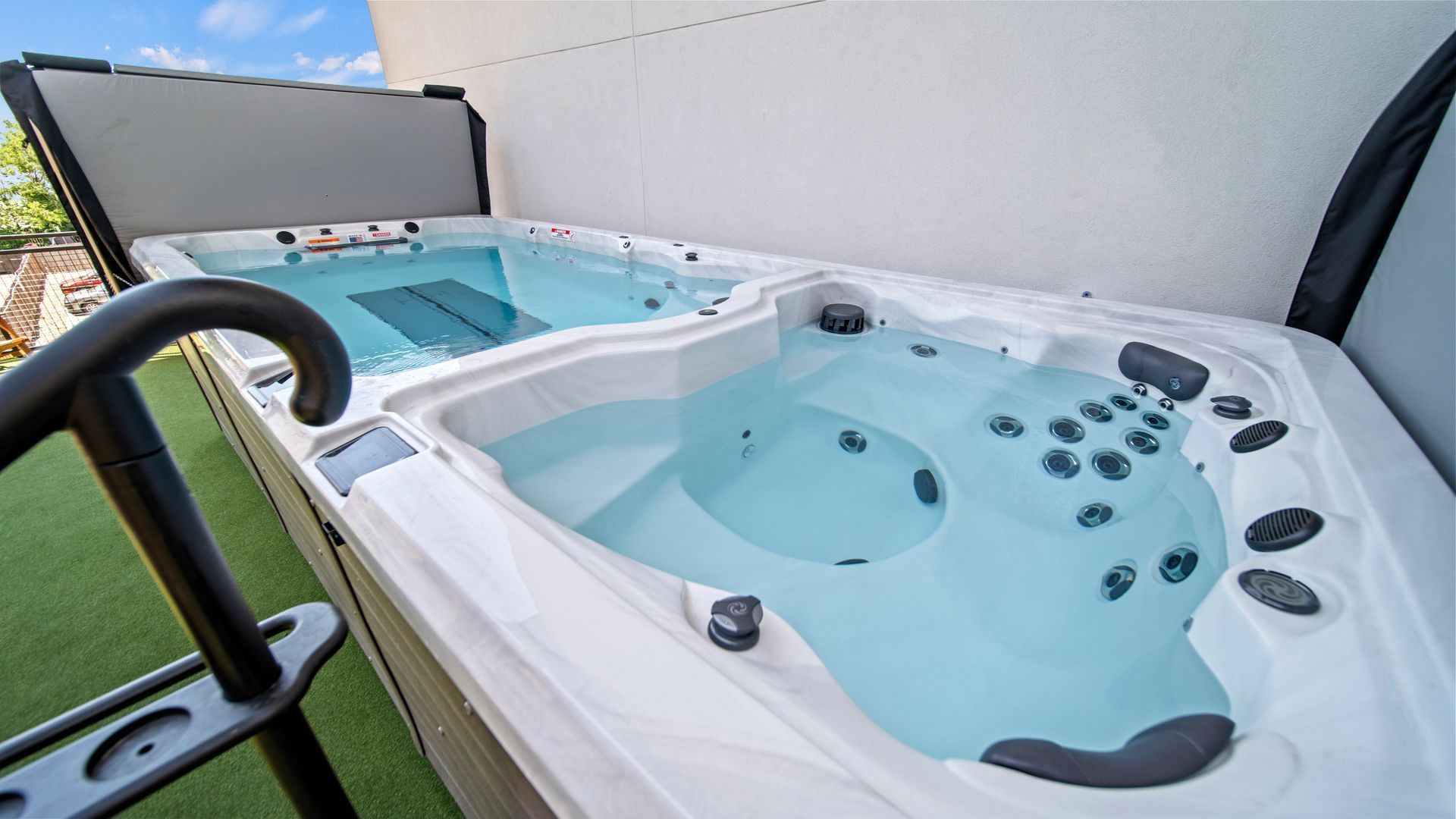 Outdoor hot tub on a rooftop terrace beside a small pool, with lounge chairs and city views.