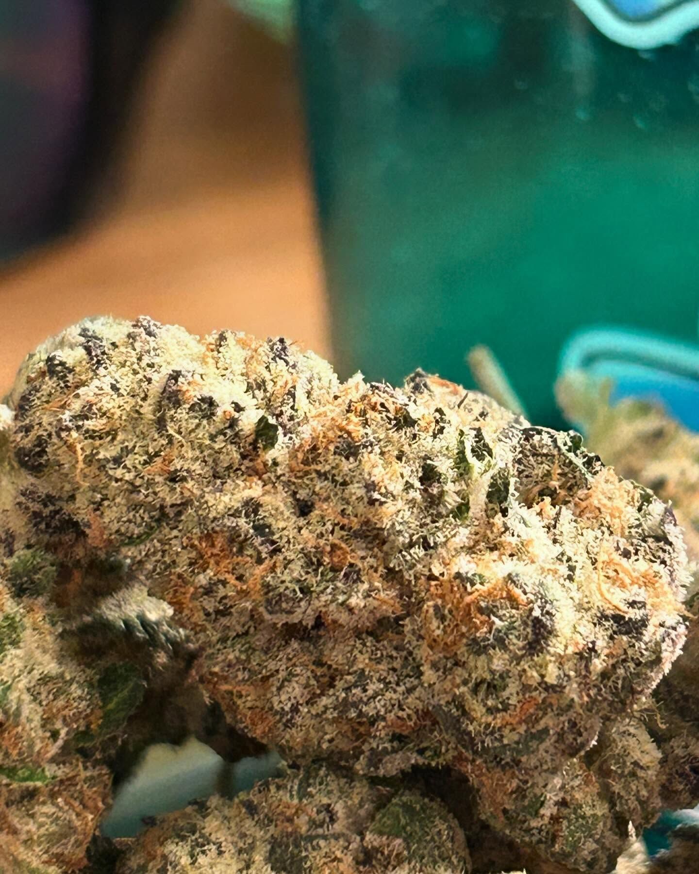 Close-up of cannabis bud with frosted appearance, orange and green hues.