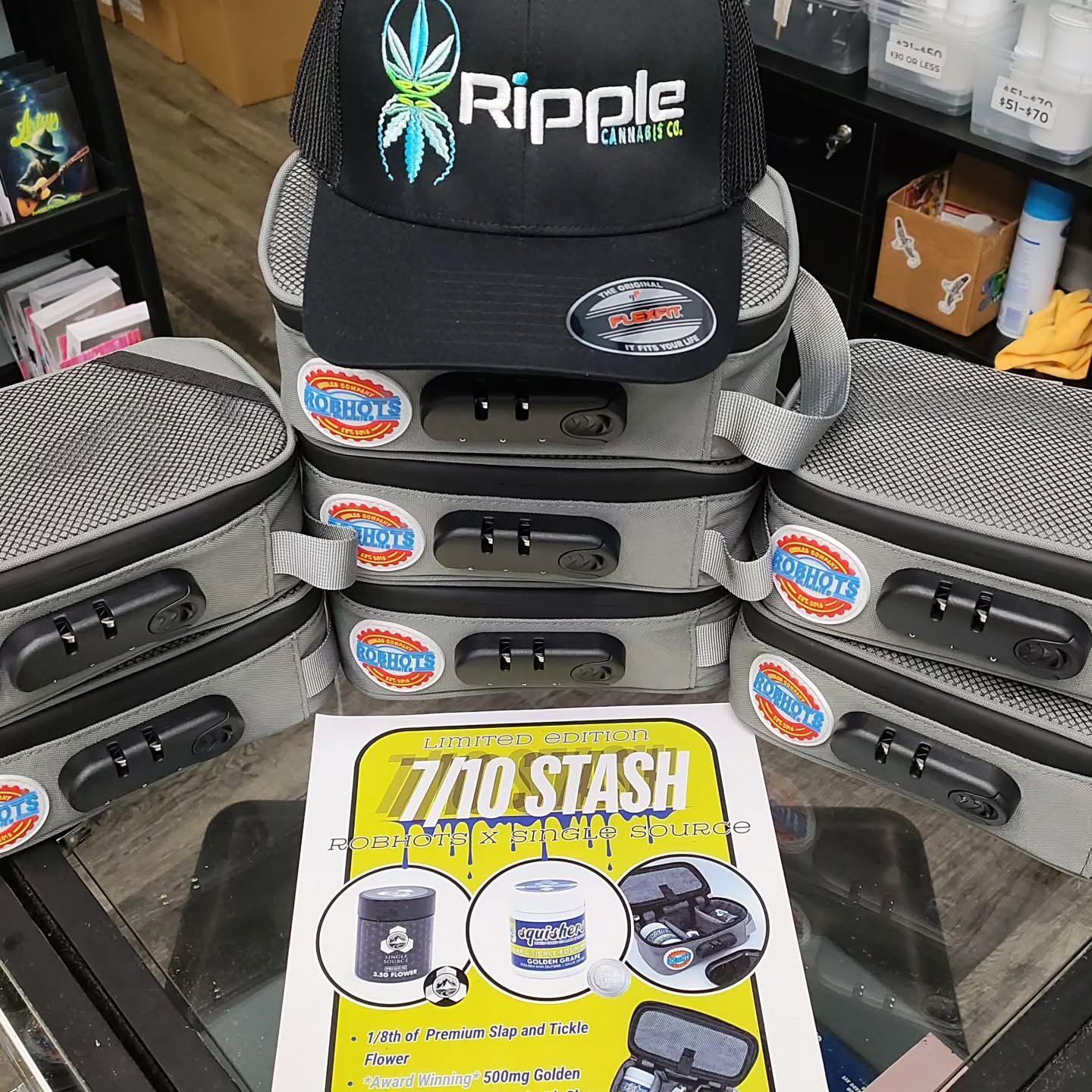 Stacked gray lockboxes with a black hat, a sign, and items for sale.