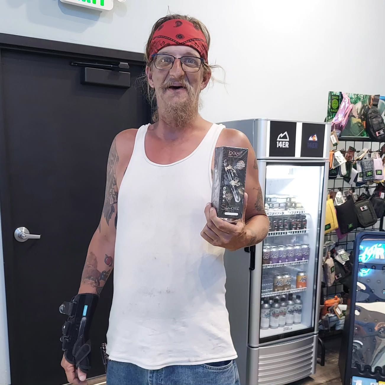 Man in tank top and bandana holding a product in a store.