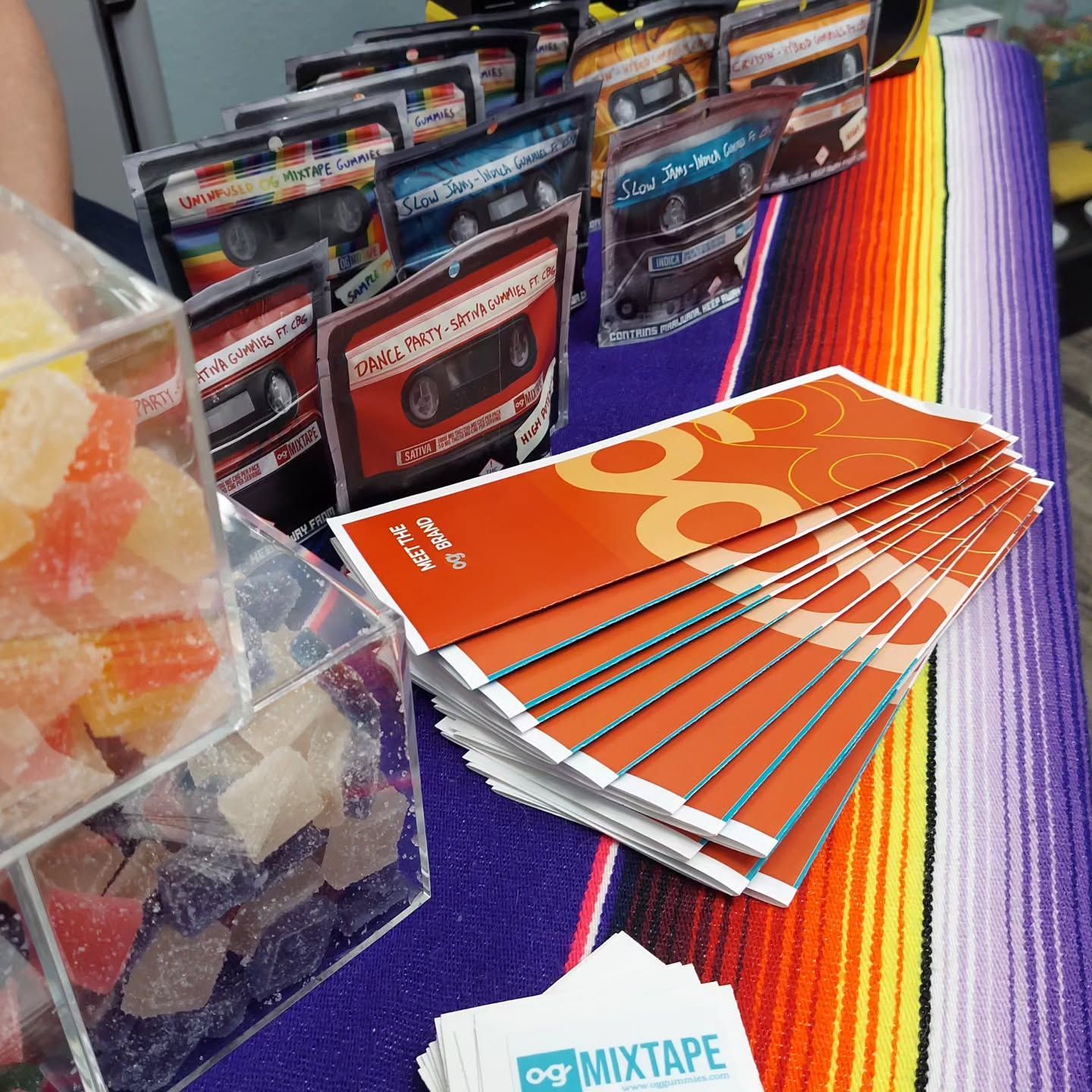 Table display with candy, cassette tapes, flyers, and a multi-colored serape.