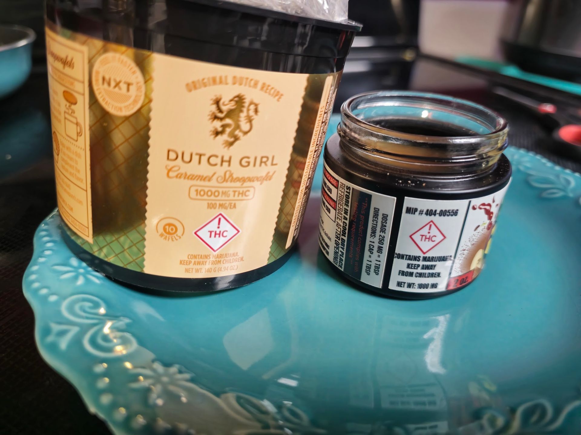 Two Dutch Girl edibles: Caramel Stroopwafel jar and a small jar on a teal plate.