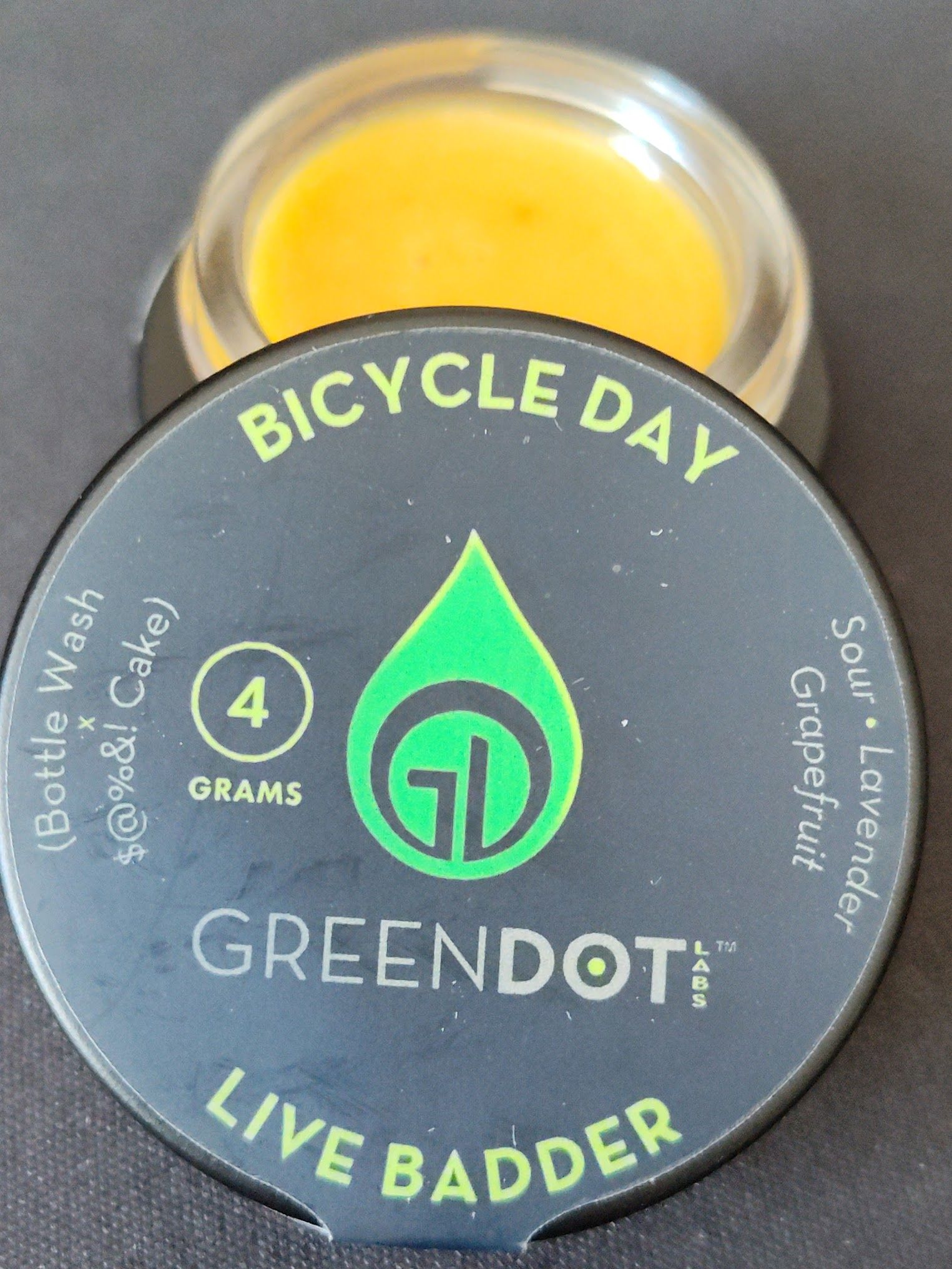 A jar of yellow concentrate with a black lid labeled 