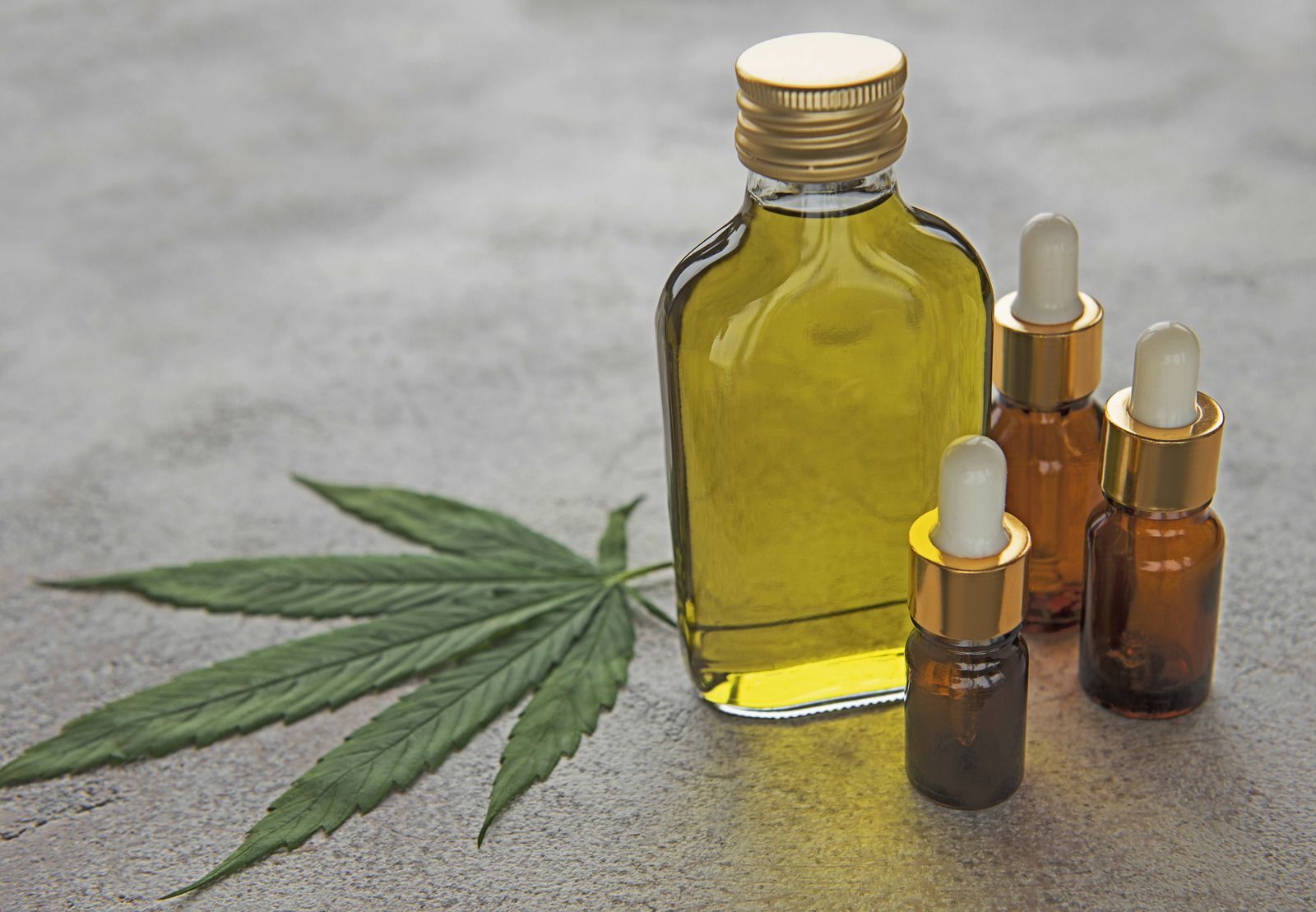 Person dripping liquid from a dropper onto their wrist, holding a small brown bottle, on a countertop.