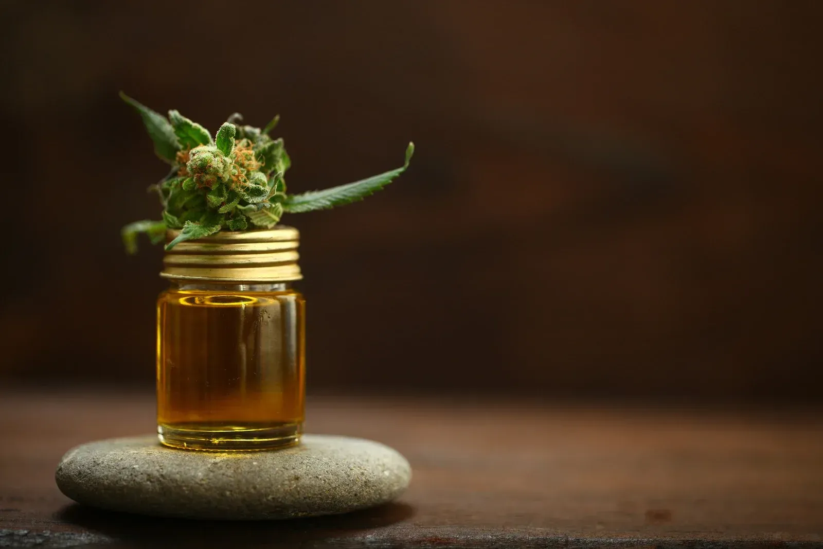 Brown bottle with dropper dispensing liquid near fresh mint sprigs.
