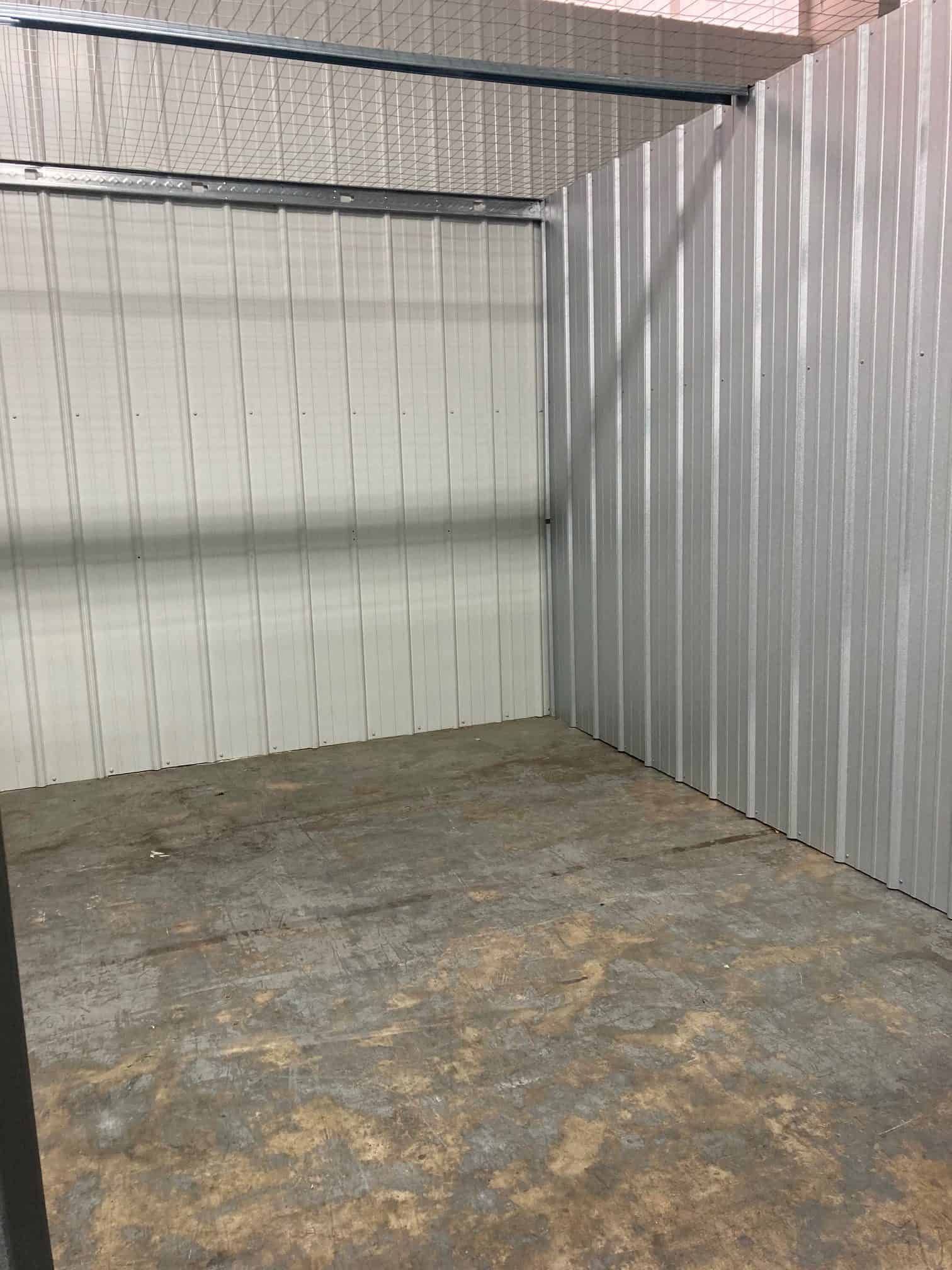 An empty room with a metal wall and a concrete floor.