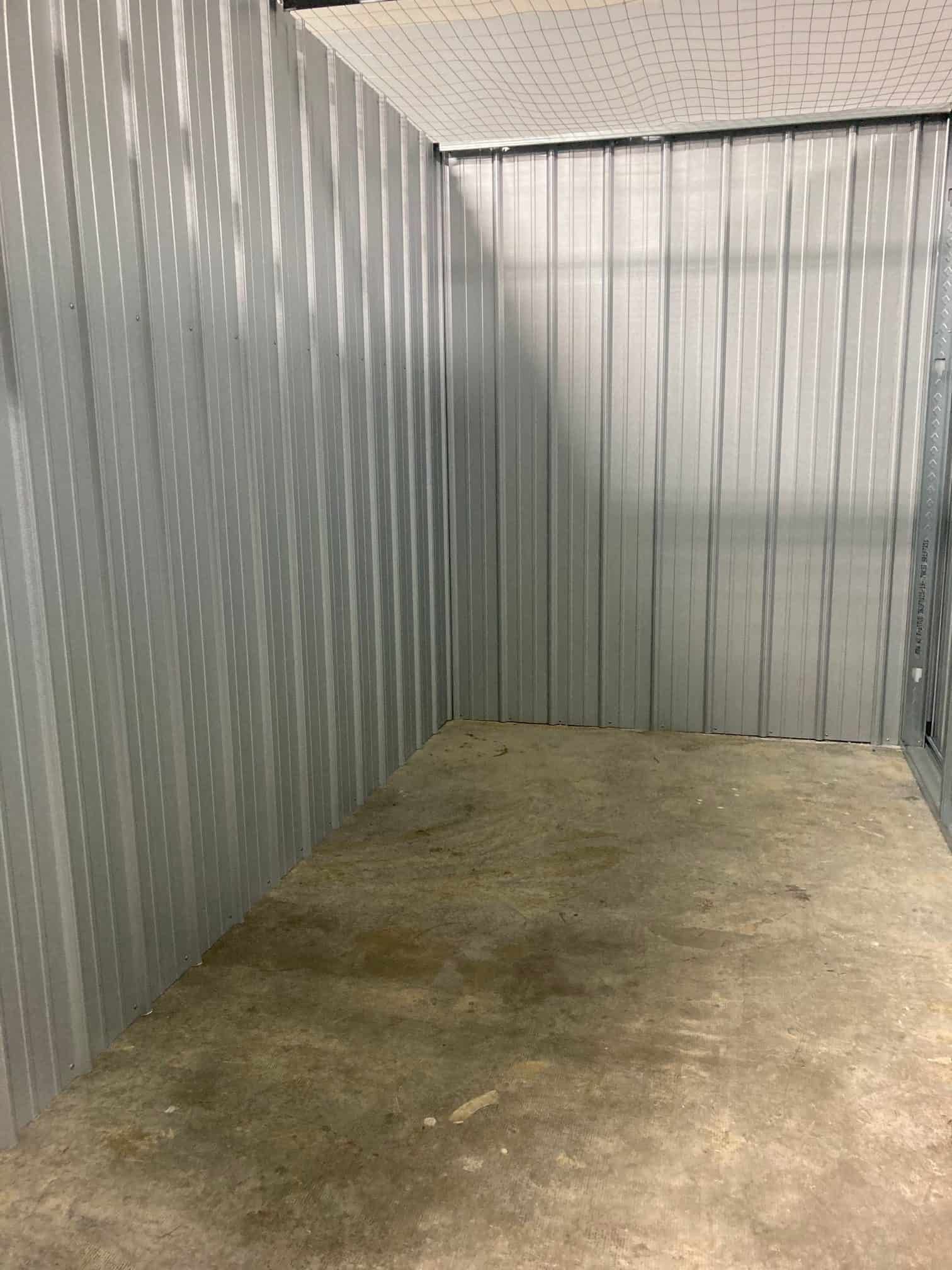 An empty room with a concrete floor and a metal wall.