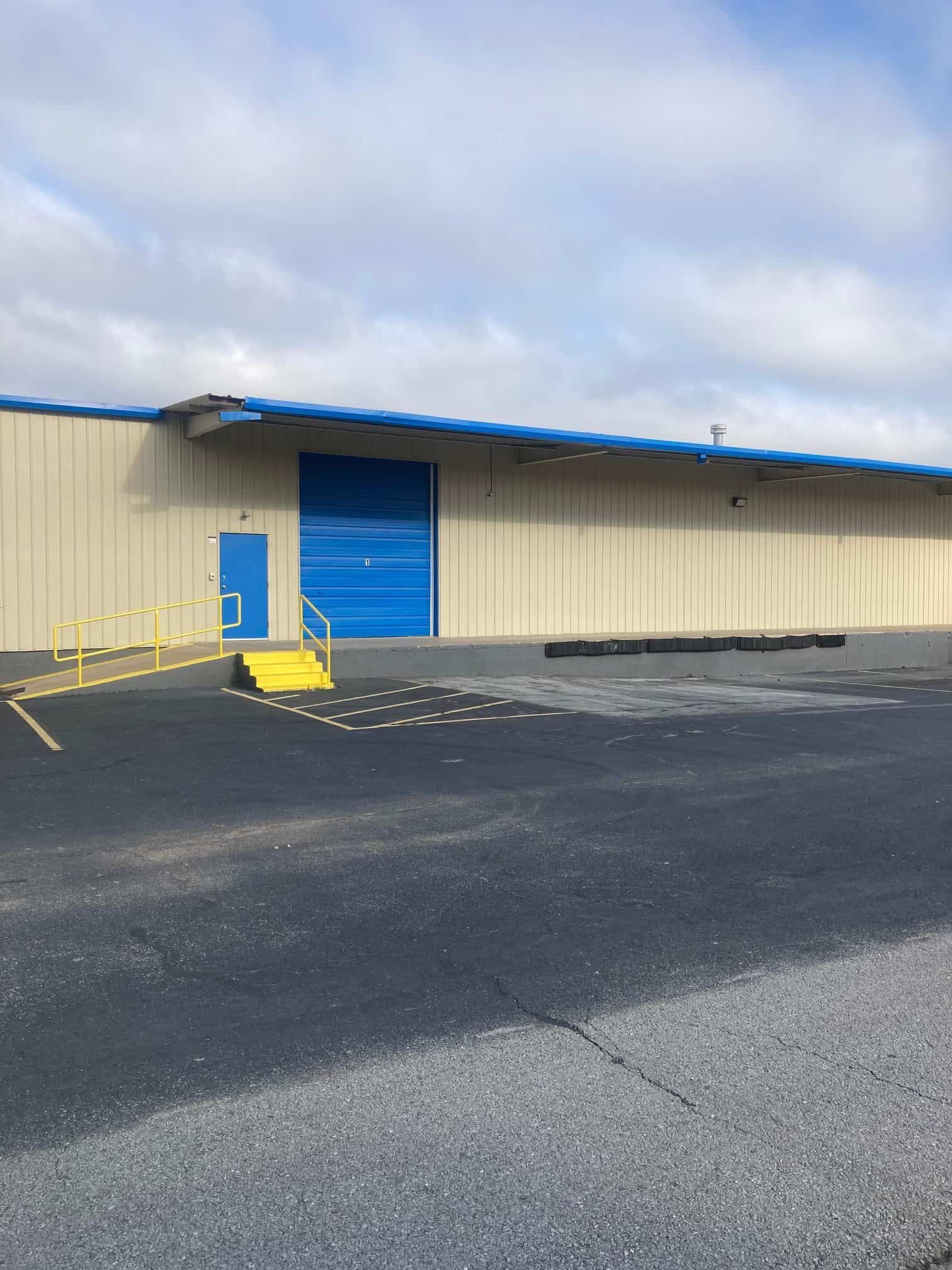 A large building with a blue door and a ramp in front of it.