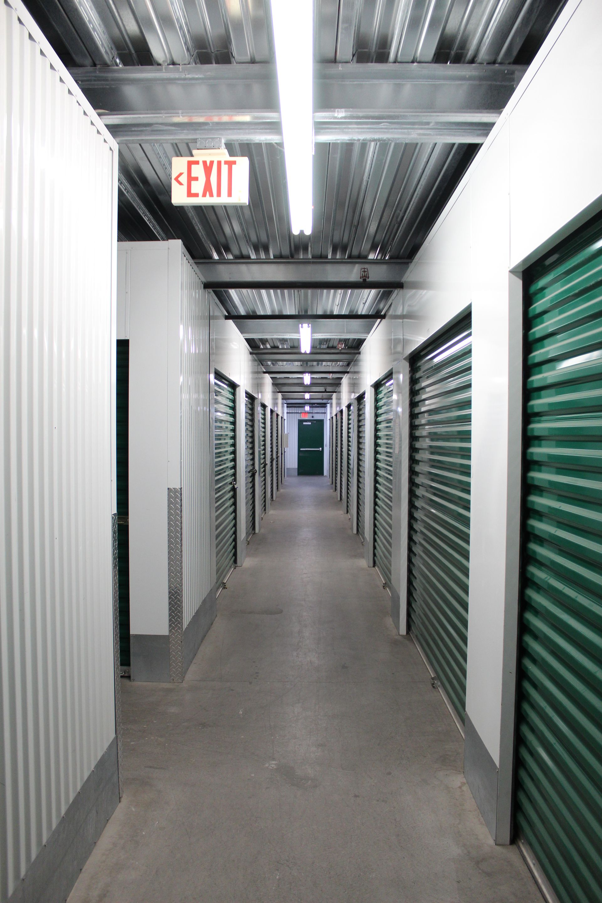 A long hallway with a red exit sign on the ceiling