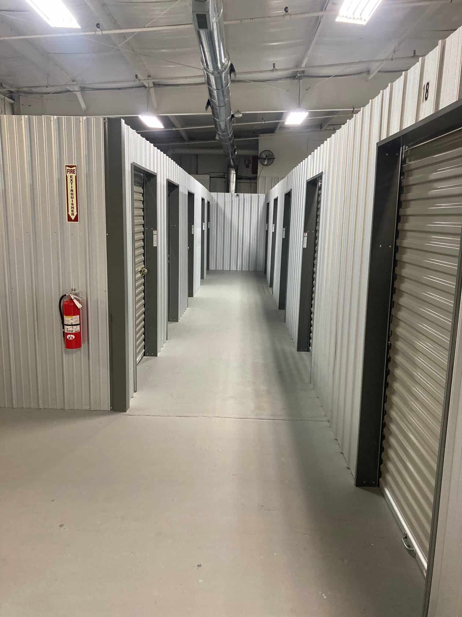 A long hallway in a building with a fire extinguisher on the wall.