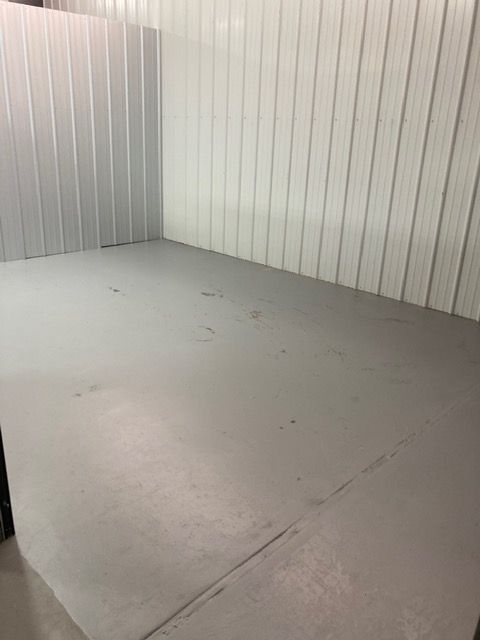 A man is holding a cardboard box in front of a storage unit.