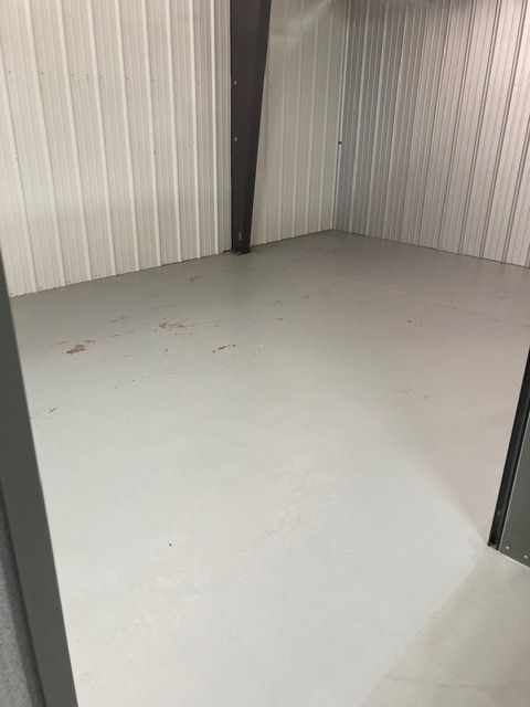 A small empty garage with a desk and chair inside of it.