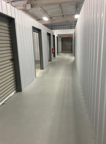 A man and a woman are carrying boxes into a storage unit.