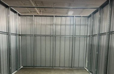 A woman is carrying a cardboard box in front of a storage unit.