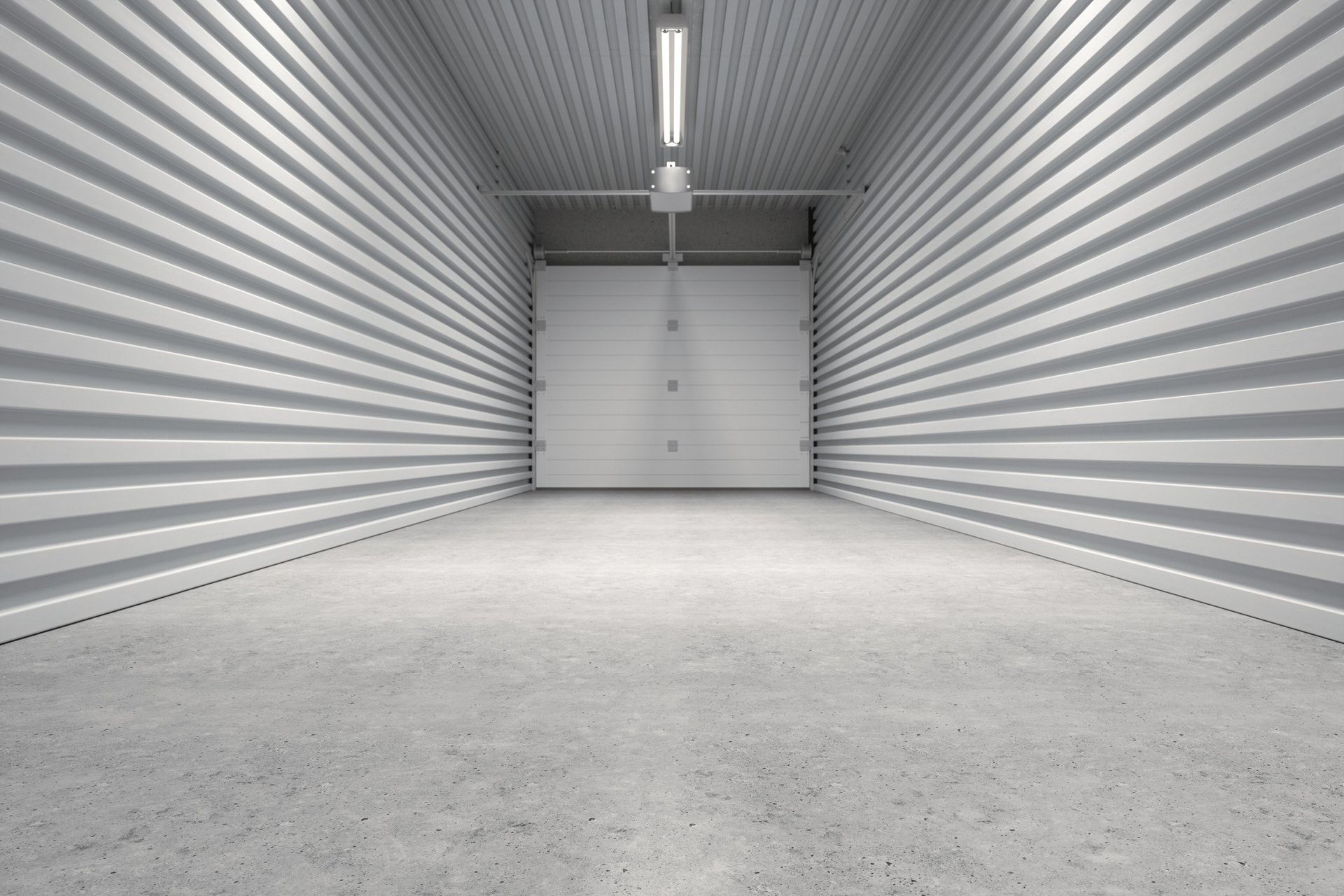 An empty garage with a white garage door and concrete floor.