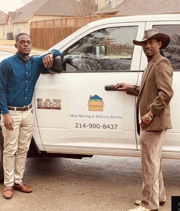 Two men stand by a white moving truck branded with a logo and phone number, posing for a business photo outdoors.
