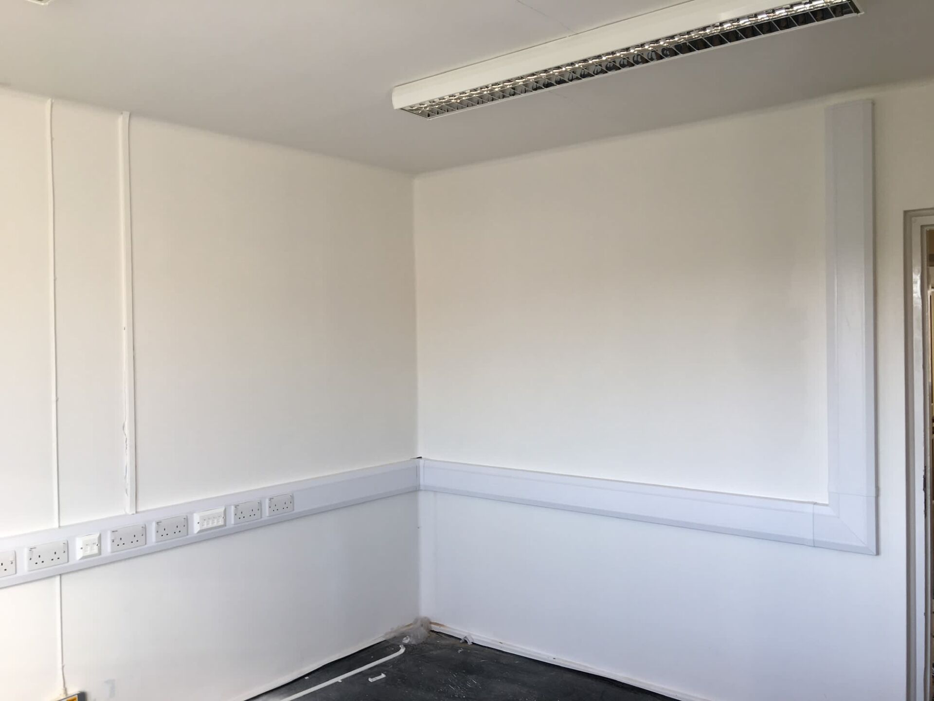 Sockets added to white wall and neatly covered by white plastic frame