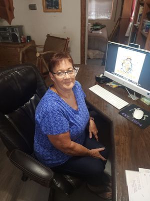Woman sitting at a desk with a computer, smiling. 