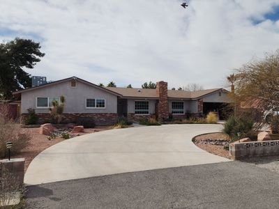 A single-story house with a long driveway under a cloudy sky.