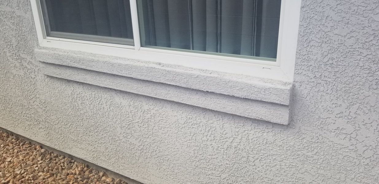 Exterior of a building with a window and textured stucco siding. 