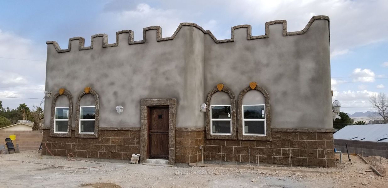A castle-like building with stone and stucco exterior, arched windows, and a crenelated roof.