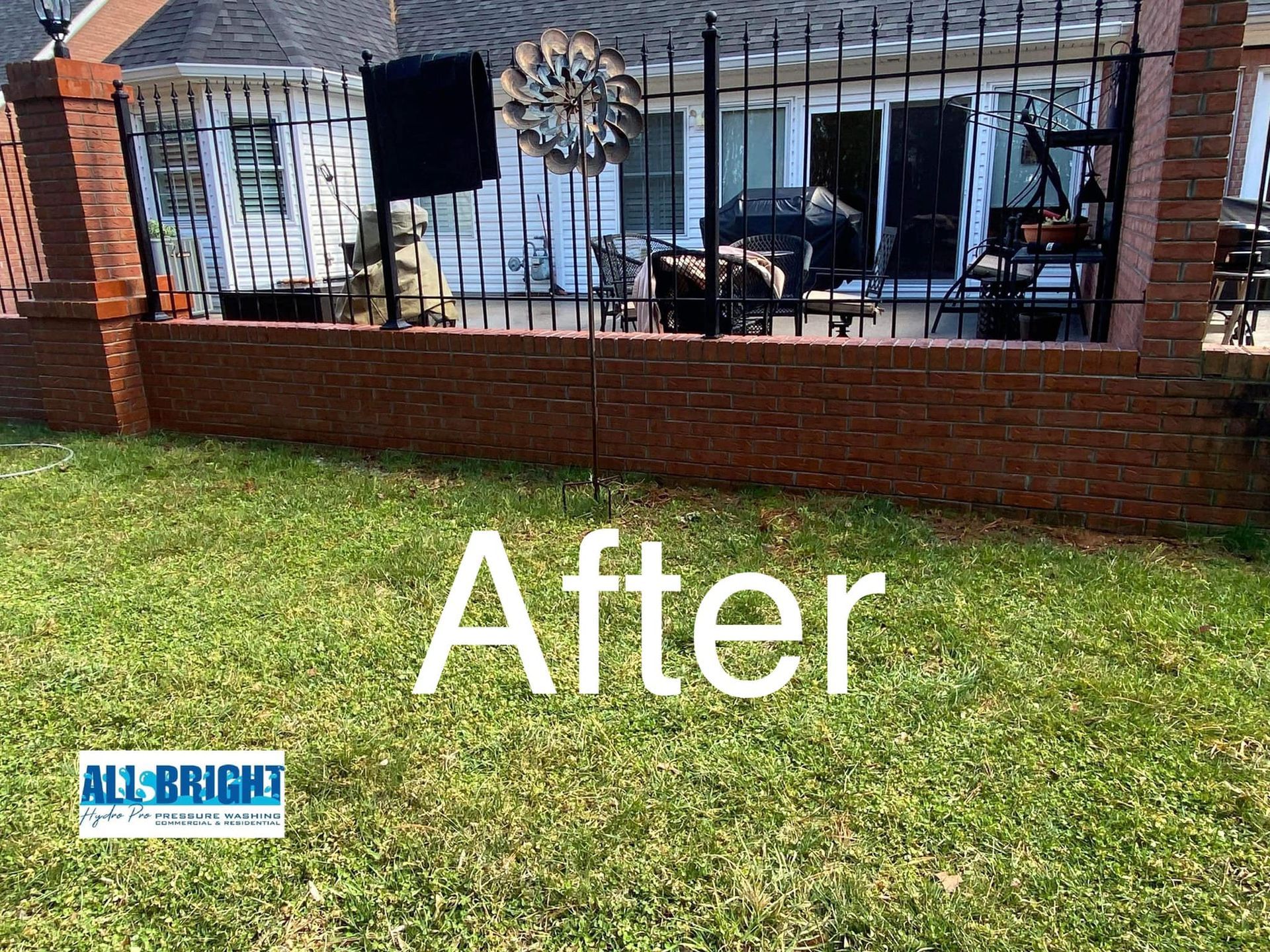 A picture of a house with a fence and a brick wall after being cleaned.