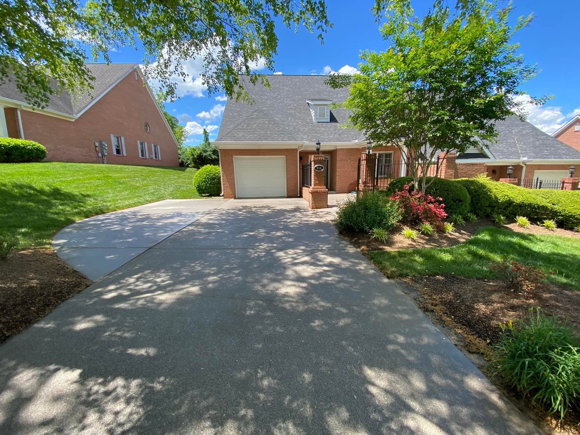 A driveway leading to a brick house with a white garage door.