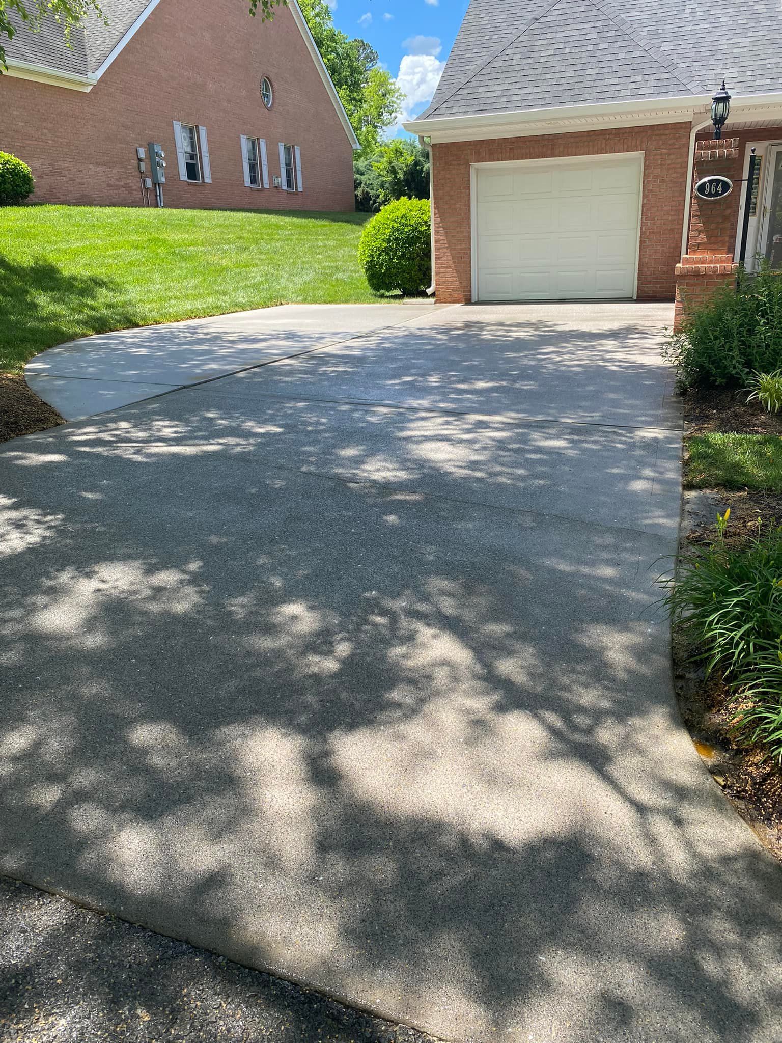 A driveway leading to a garage with a brick house in the background.