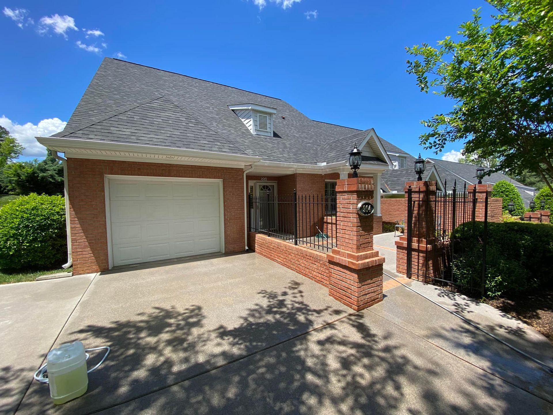 A brick house with a white garage door and a fence