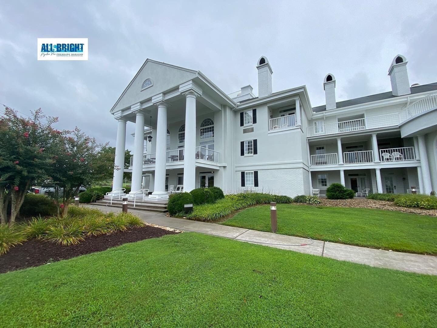 A large white building with columns and a lush green lawn in front of it.