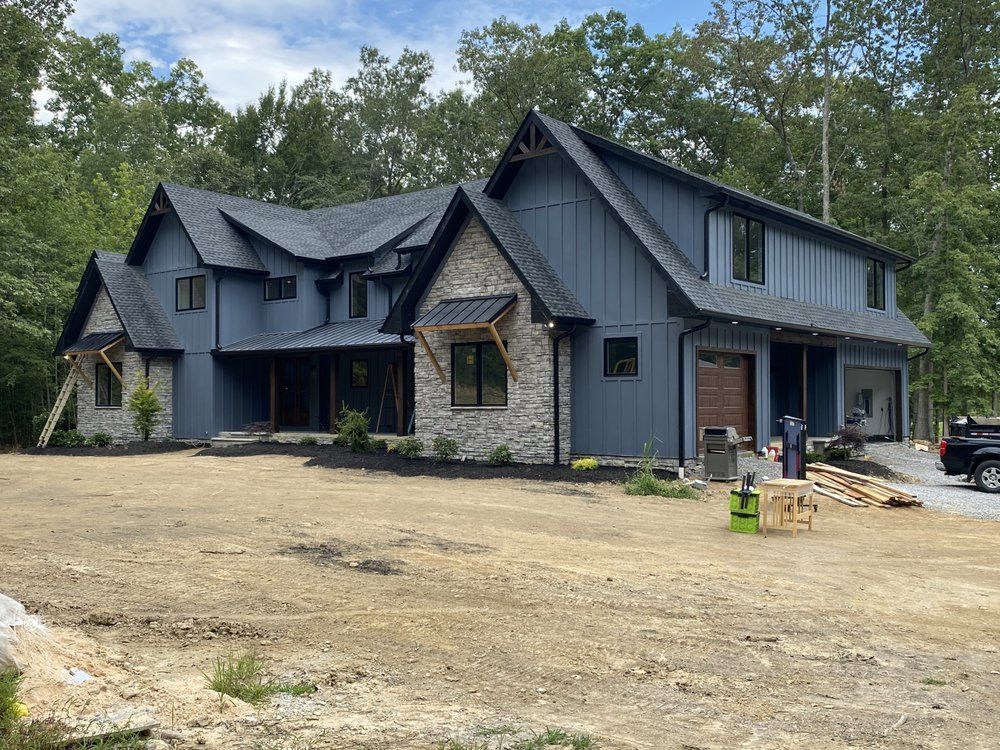 A large blue house with a black truck parked in front of it.