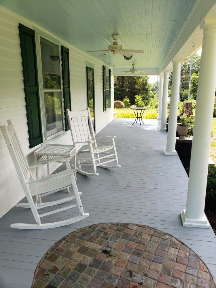 There are two rocking chairs on the porch of a house.