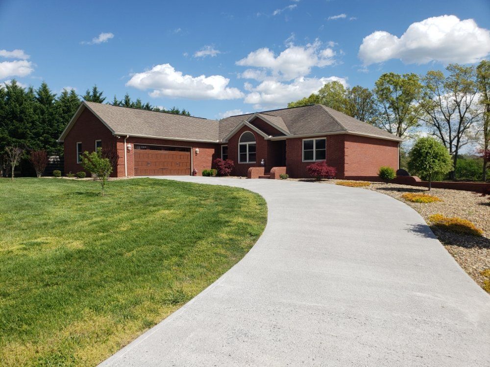 A brick house with a concrete driveway leading to it