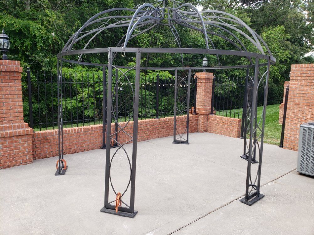 A gazebo is sitting on a concrete patio next to a brick wall.