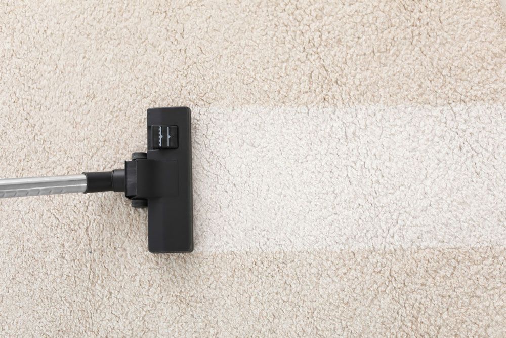 A Vacuum Cleaner Is Cleaning A White Carpet — Affordable Carpets Woolgoolga In Woolgoolga, NSW