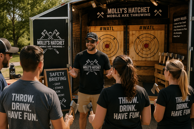 A group stands before a mobile axe throwing trailer while a staff member gives a safety briefing in an outdoor setting.